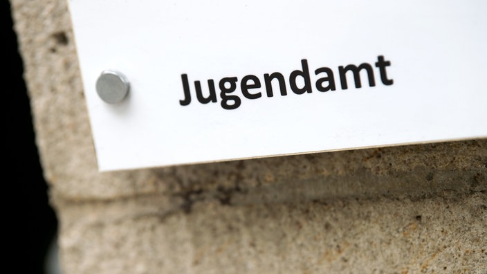 Ein weißes Schild an einer Mauer mit der Aufschrift "Jugendamt".
