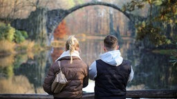 Symbolbild junge Menschen in Ostdeutschland: eine junge Frau und ein junger Mann schauen auf die Rakotzbrücke in Gablenz-Kromlau im Landkreis Görlitz in Sachsen