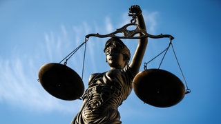 Eine Fotografie einer Justitia-Statue vor blauem Himmel mit hohem Kontrast aus einer Untersicht.