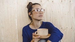 Eine Frau mit einer Tasse Kaffee macht eine Pause.