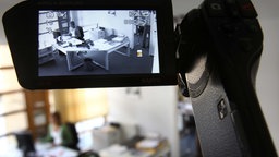 Eine Videokamera zeichnet in einer gestellten Szene die Arbeit in einem Büro auf.