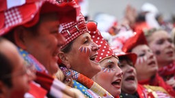 Karnevalsjecken im Karnevalskostüm stehen in einer Reihe nebeneinander und singen.