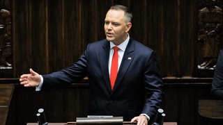 Karol Nawrocki steht am Rednerpult und spricht, dabei unterstreicht er seine Worte mit einer Geste in Richtung Publikum.