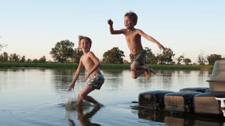 Zwei Jungen springen in einen See