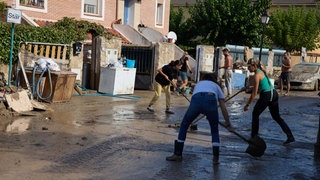 Menschen räumen nach extremen Wetter die Straße auf.