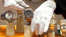 Mit weißen Handschuhen werden Uhren der Schweizer Marke Rolex in einem Schaufenster platziert. 