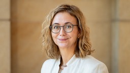 Das Porträt von Martina Wersig zeigt sie mit Brille, strukturiertem Haar und einem freundlichen Lächeln.