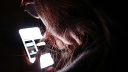 Symbolbild Mediensucht: Eine junge Frau bedient ihr Smartphone (gestellte Szene).