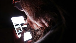 Symbolbild Mediensucht: Eine junge Frau bedient ihr Smartphone (gestellte Szene).