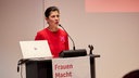 Murielle Guéguen steht an einem Podium und spricht in ein Mikrofon.