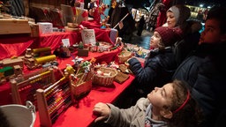 Familie Kara mit Mutter Tuba (2.v.r),und den Kindern Meryem (M), Talia (unten) und Yusa (r) betrachten auf dem Weihnachtsmarkt einen Stand. 