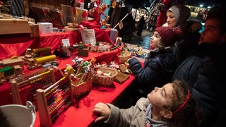 Familie Kara mit Mutter Tuba (2.v.r),und den Kindern Meryem (M), Talia (unten) und Yusa (r) betrachten auf dem Weihnachtsmarkt einen Stand. 