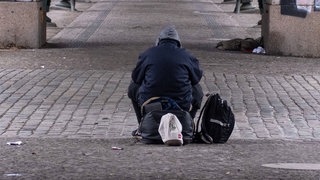 Ein Obdachloser sitzt an einer Unterführung.