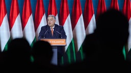 Viktor Orbán spricht vor einem Publikum mit ungarischen Flaggen im Rücken.