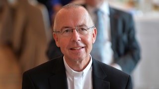 Porträtaufnahme: Der katholische Priester Peter Kossen hat lichtes Haar, trägt eine randlose Brille und einen schwarzen Anzug über einem weißen Hemd.