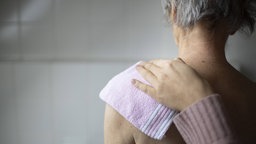 Eine Pflegerin reicht einem Pflegepatienten eine Tablette