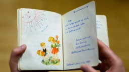 Aufgeklapptes Poesiealbum, das zwei beschriftete und bemalte Seiten zeigt. 
