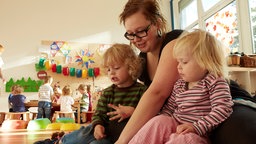 Symbolbild: Eine Betreuerin spielt mit zwei Kindern in einer Kindertagesstätte.