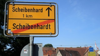 Ein Ortsschild: In einem Kilometer beginnt Scheibenhard im Elsass, wo Scheibenhardt in der Pfalz endet