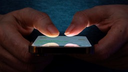 Nahaufnahme eines Smartphones, das von zwei Händen gehalten wird.