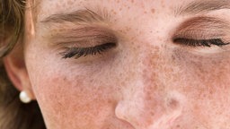 Junge Frau mit Sommersprossen und geschlossenen Augen