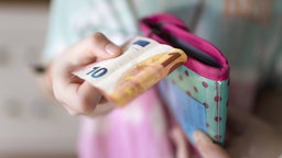 Ein Mädchen hält einen 10-Euro-Schein in der Hand