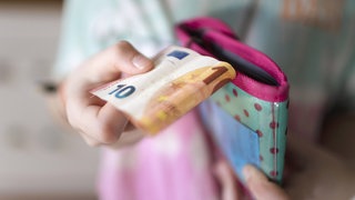 Ein Mädchen hält einen 10-Euro-Schein in der Hand