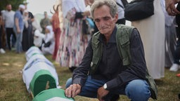 Ein Mann hockt trauernd neben dem Sarg mit den Überresten eines neu identifizierten Opfers des Srebrenica-Genozids von 1995 im Gedenkzentrum in Potočari, Bosnien.