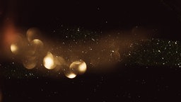 Glitzernder Staub vor schwarzem Hintergrund.