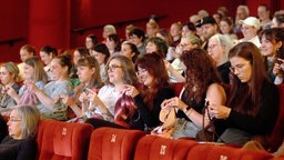 Fast ausschließlich Frauen sitzen in einem Kinosaal und stricken.