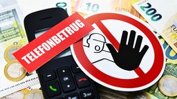 Nahaufnahme eines Telefons und von Bargeld mit einem Warnhinweis vor Telefonbetrug.