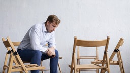 Trauriger Mann Gruppentherapiesitzung mit leeren Stühlen.