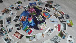 Um eine Bumenvase auf dem Boden liegen Fotos, Postkarten und Bilder