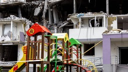 Zerstörte Häuser in Bucha Amid in der Ukraine, davor ein Kinderspielplatz