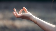 Zeigefinger und Daumen formen einen Kreis beim Meditieren