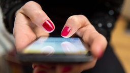  Eine Frau tippt auf einem Smartphone.