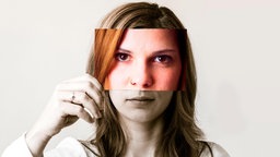 eine Frau hält ein Foto mit ihrem Gesicht vor ihr Gesicht