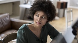 Junge Frau mit dunklen Haaren schaut ernst und nachdenklich