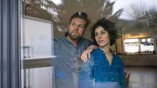 Ein Paar steht nachdenklich am Fenster und blickt in eine Richtung