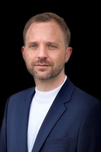 Carsten Lotz im Anzug mit schwarzem Hintergrund