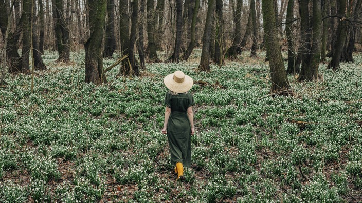 Eine Frau mit großem Hut im Wald