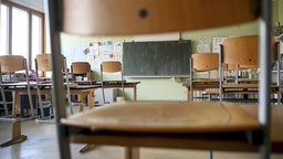 Ein leeres Klassenzimmer, in dem die Stühle hochgestellt sind.