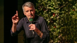 Johannes Flöck mit Mikrofon auf der Bühne.
