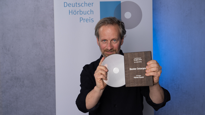 Fabian Busch hält den Preis in den Händen.