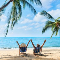 Glückliches Paar mit erhobenen Armen entspannen am Strand und genießen das Meer auf einer tropischen Insel. 