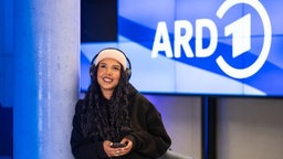 Junges Mädchen hört ein Programm der ARD über ein Smartphone. 