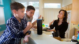 Zwei Jungen und ihre Mutter spielen mit Alexa. 