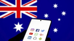 Smartphone wird vor eine Australische Flagge gehalten. 