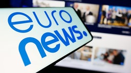Smartphone mit Logo des  Fernsehsenders Euronews vor einer Unternehmenswebsite, 10.04.2024