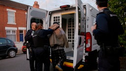 Eine Person wird von Beamten der Einwanderungsbehörde in einen PKW geschoben, 01.05.2024.